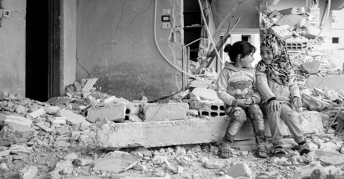 Crisis Action annual report 2017 cover - two girls in a bombed-out building in Syria